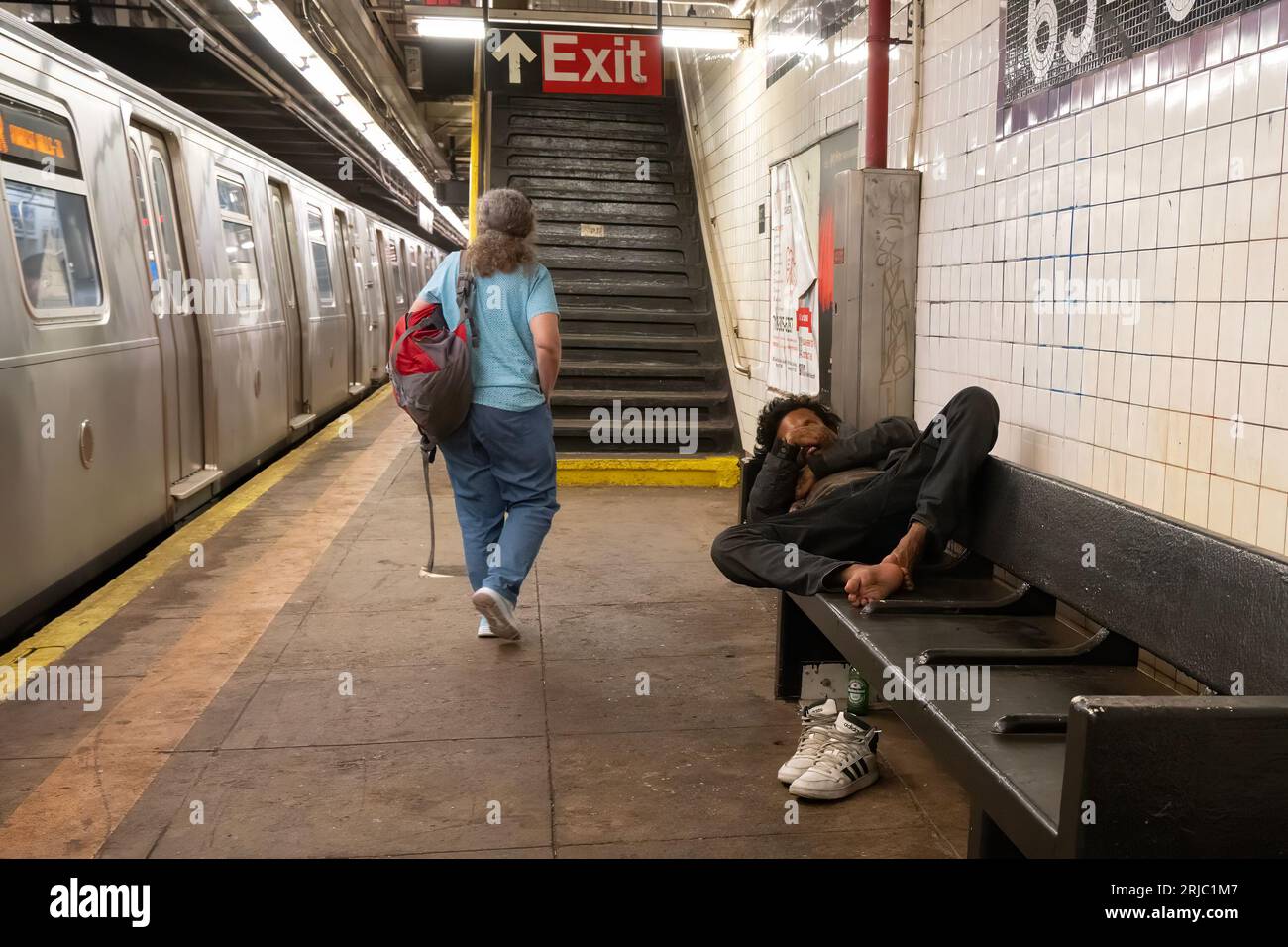 New York, USA - July 20th, 2023: A man sleeping on a bench in a subway station in New York city. Stock Photo