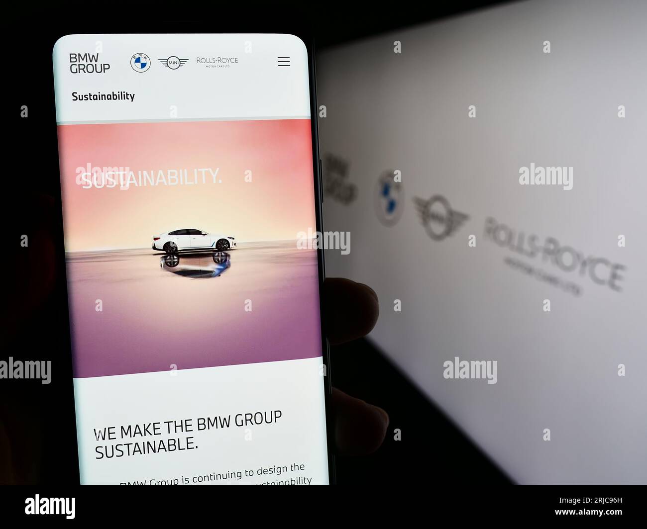 Person holding smartphone with webpage of company Bayerische Motoren Werke AG (BMW Group) on screen with logo. Focus on center of phone display. Stock Photo