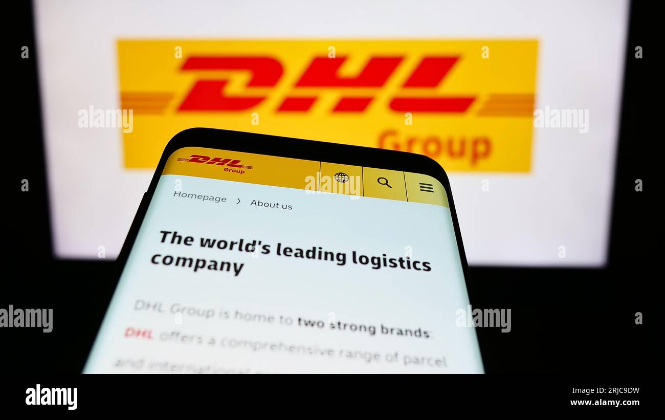 Mobile phone with website of logistics company Deutsche Post AG (DHL Group) on screen in front of logo. Focus on top-left of phone display. Stock Photo