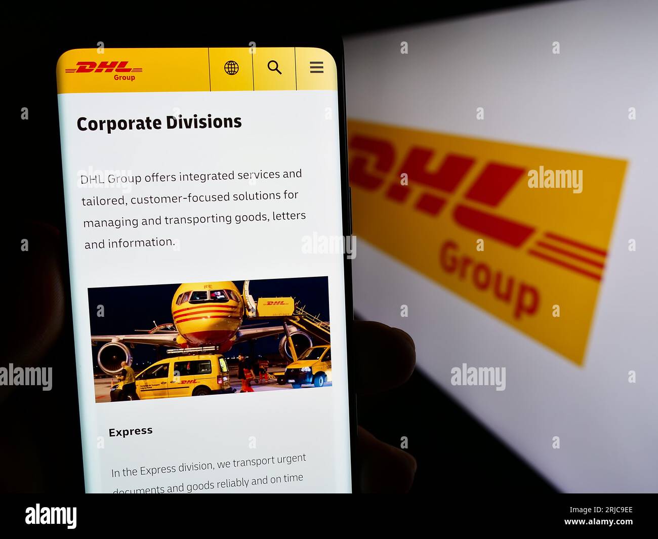 Smartphone with web page of logistics company Deutsche Post AG (DHL Group) on screen in front of logo. Focus on center of phone display. Stock Photo
