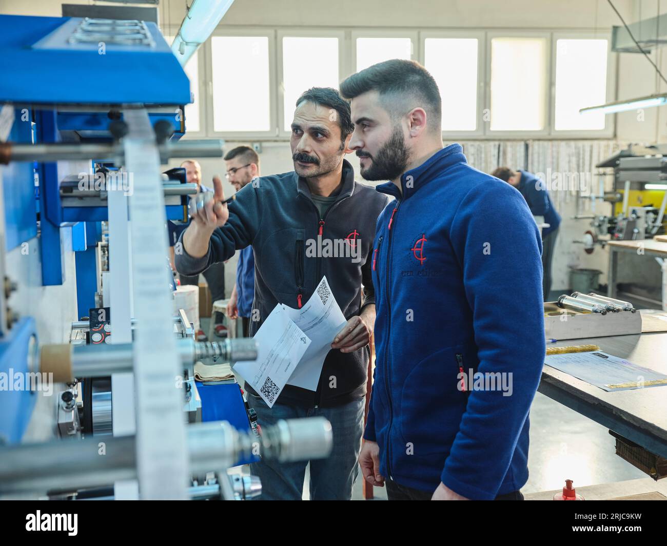 people working in a sticker printing factory. worker uses a stickier ...
