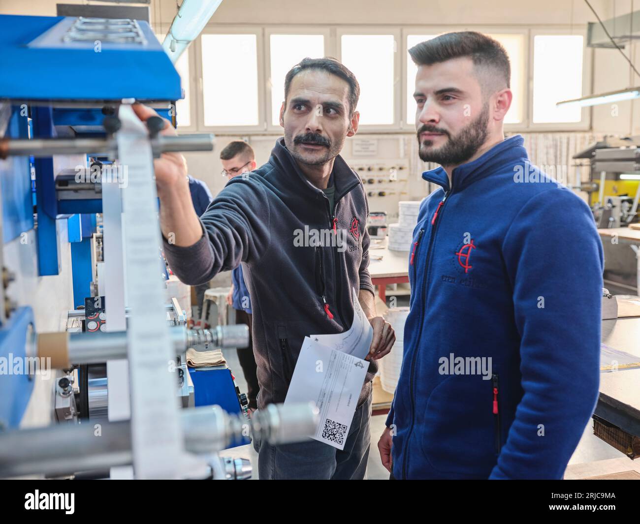people working in a sticker printing factory. worker uses a stickier ...