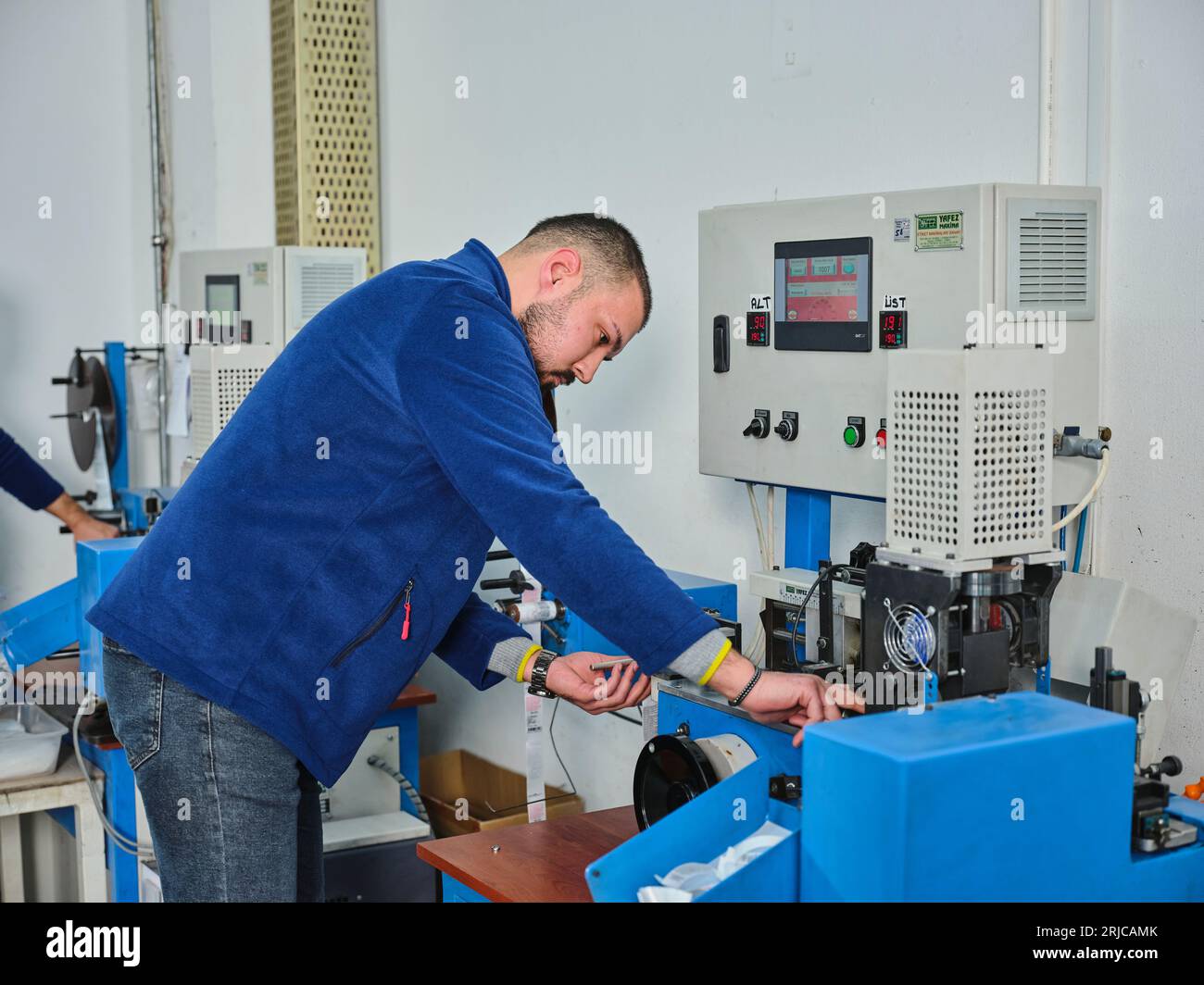 people working in a sticker printing factory. worker uses a stickier ...