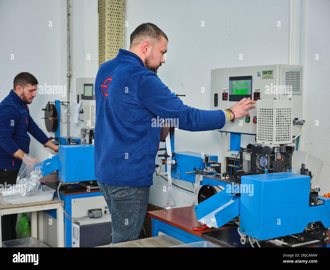 people working in a sticker printing factory. worker uses a stickier ...