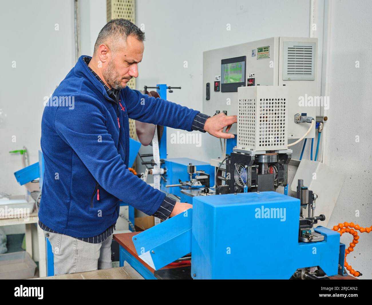people working in a sticker printing factory. worker uses a stickier ...