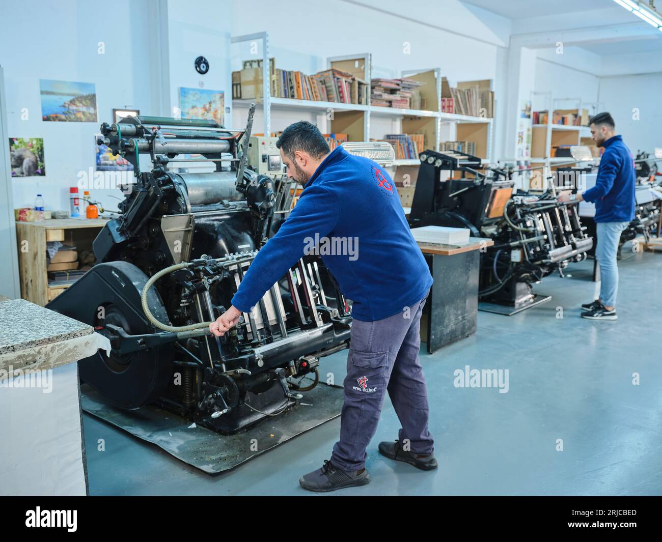 people working in a sticker printing factory. worker uses a stickier ...