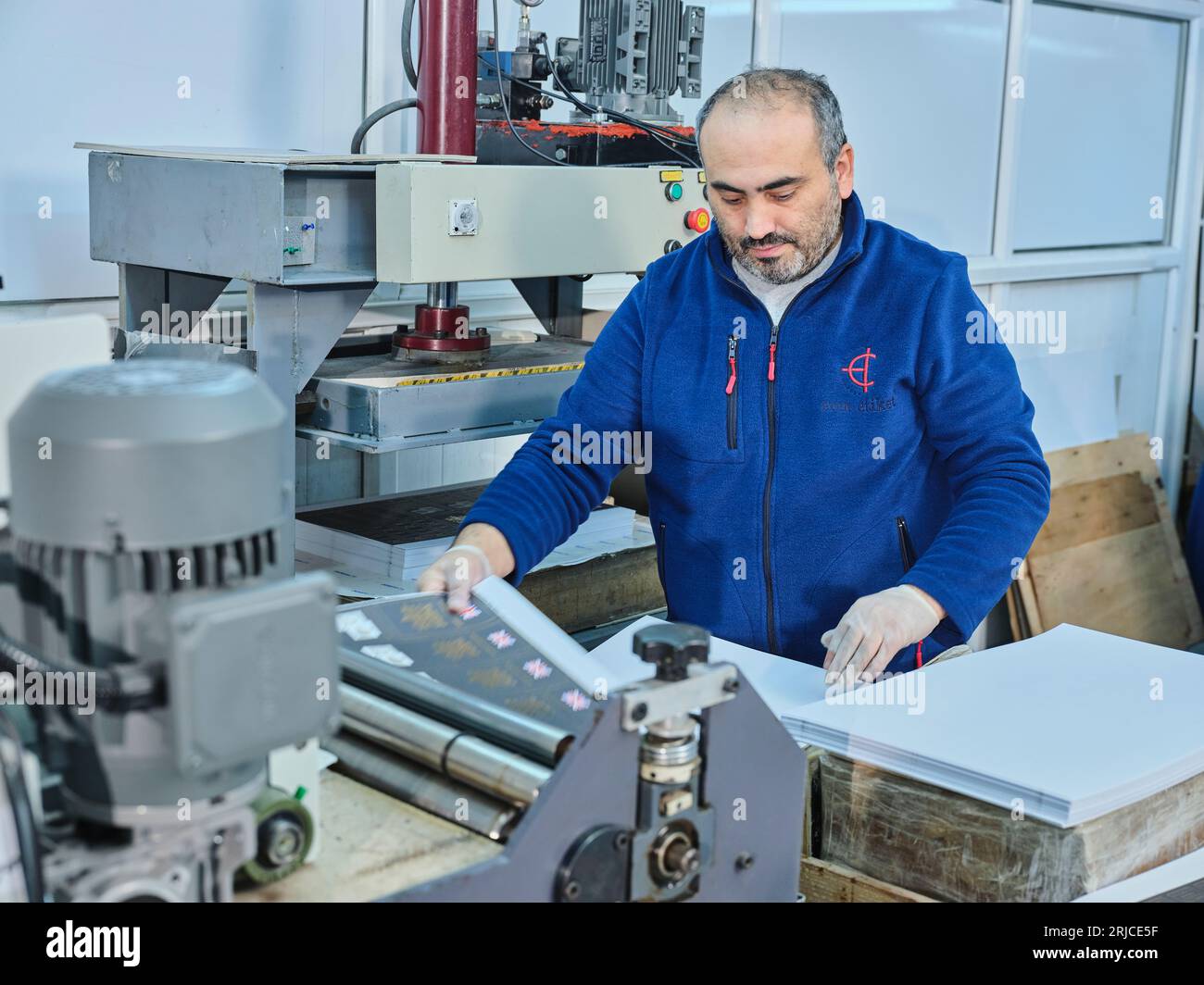 people working in a sticker printing factory. worker uses a stickier ...