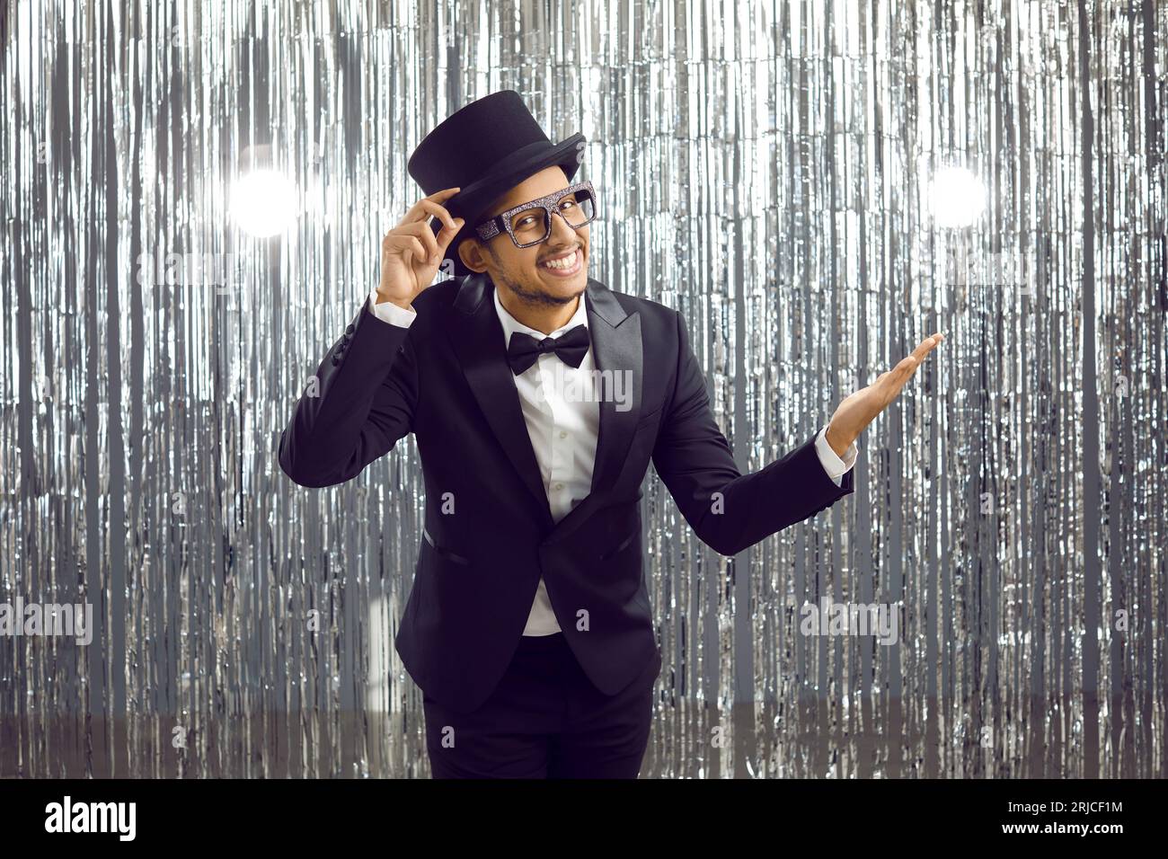 Portrait of positive young dark-skinned man who politely greets you holding on to his top hat. Stock Photo