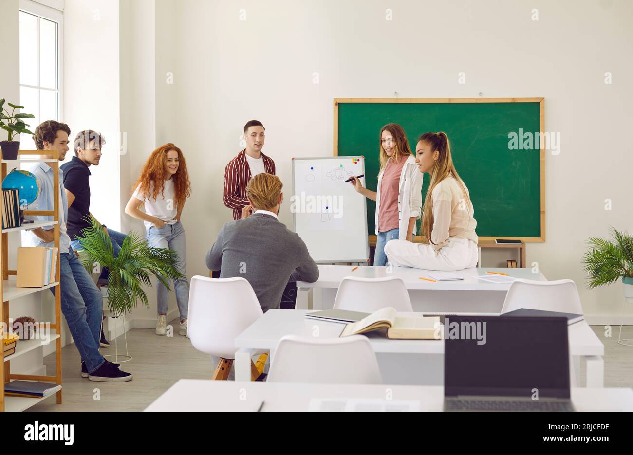 Students discussing study project with lecturer. Girl presenting project during class lesson Stock Photo