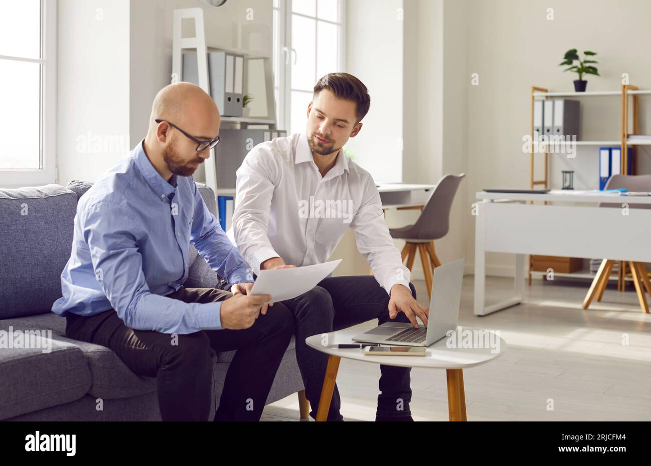 Two men sitting on sofa hi-res stock photography and images - Alamy