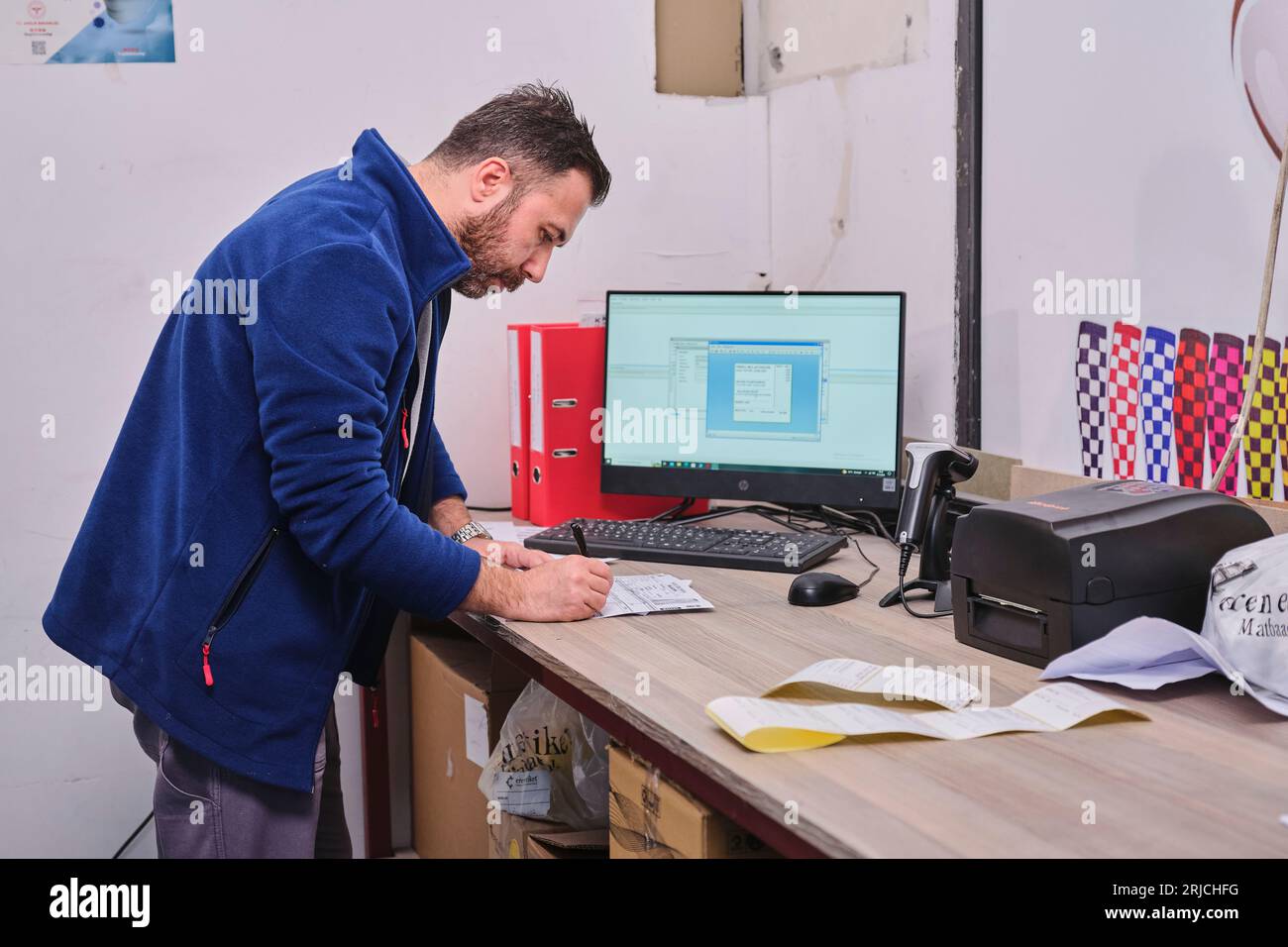 people working in a sticker printing factory. worker uses a stickier ...