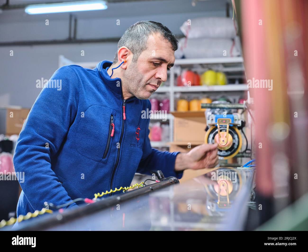 people working in a sticker printing factory. worker uses a stickier ...