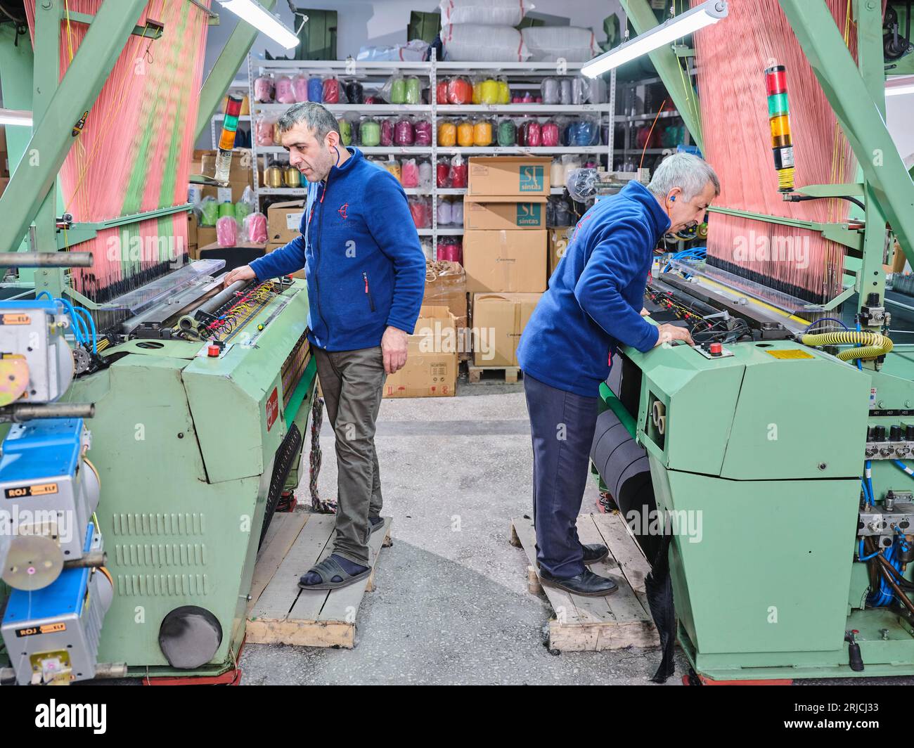 people working in a sticker printing factory. worker uses a stickier ...