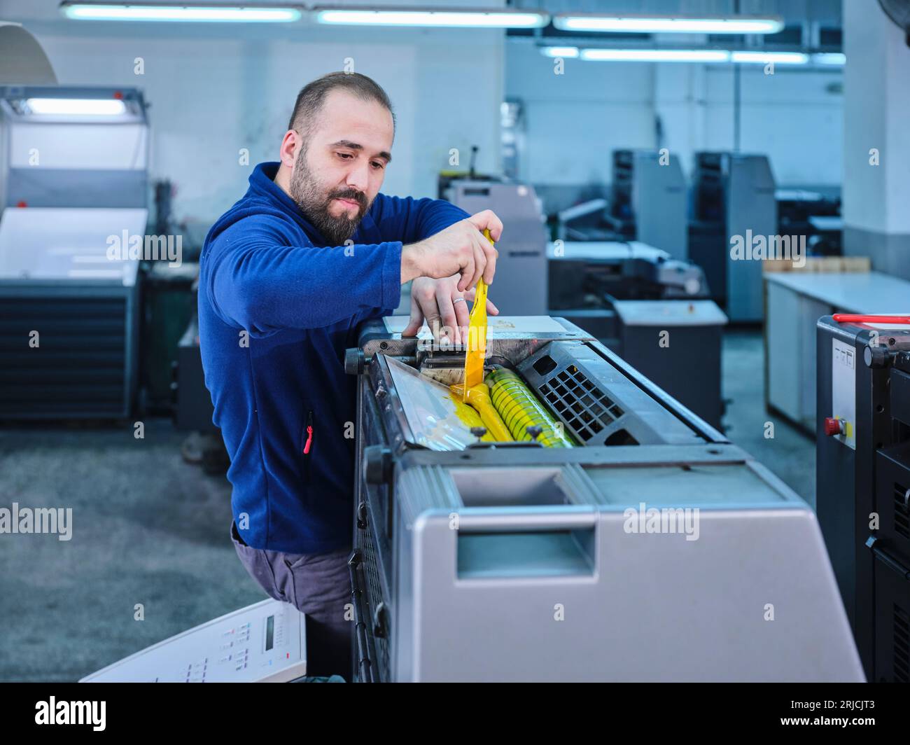 people working in a sticker printing factory. worker uses a stickier ...