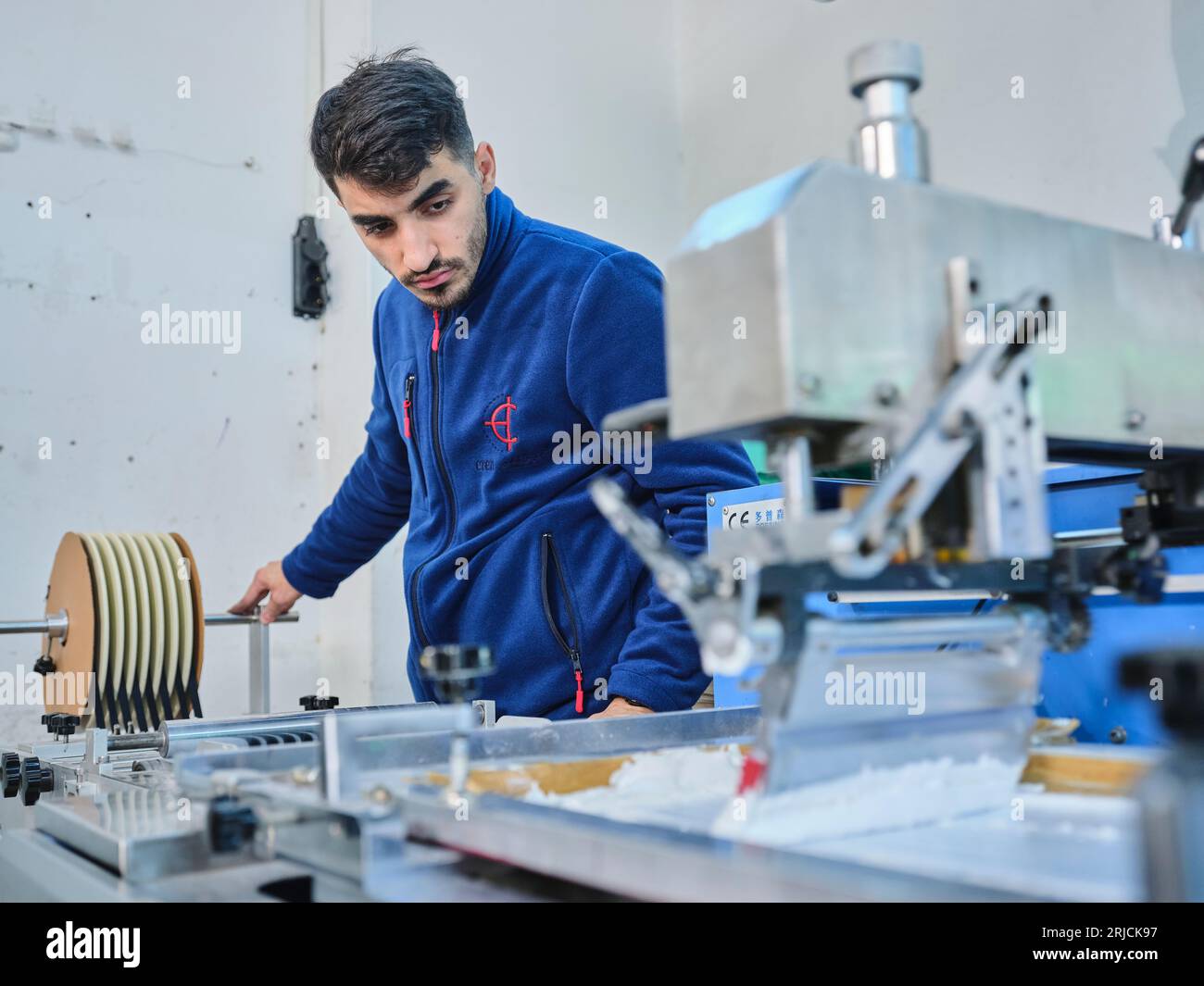 people working in a sticker printing factory. worker uses a stickier ...