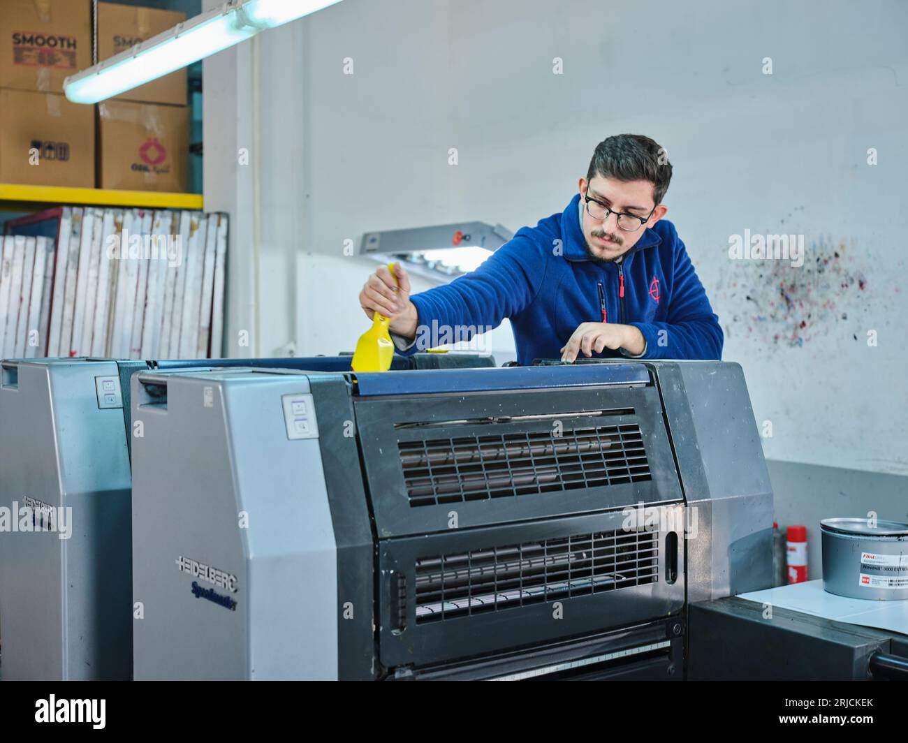 people working in a sticker printing factory. worker uses a stickier ...