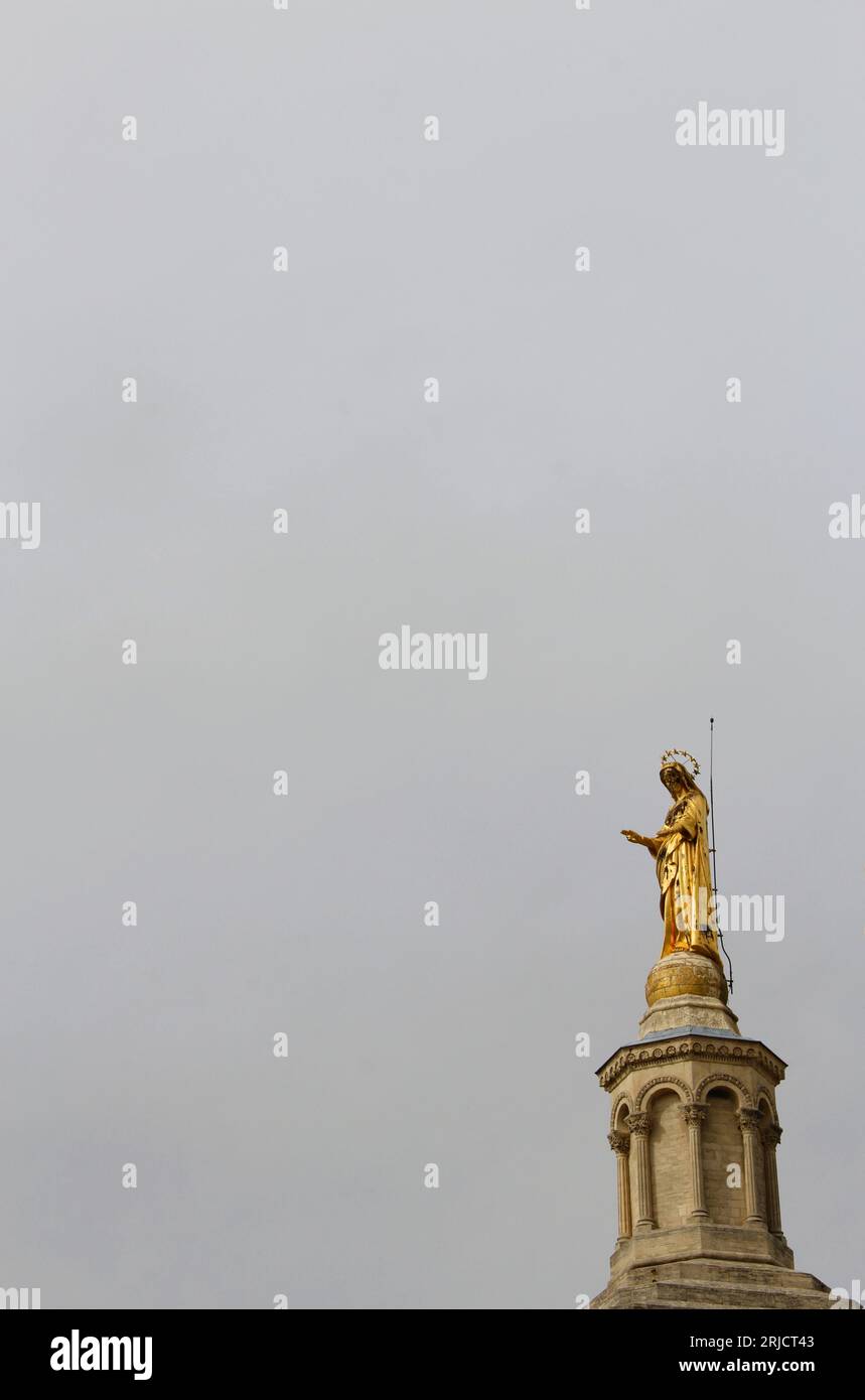 The golden statue of the Virgin Mary atop the cathedral at Palais des Papes (Popes' Palace), in Avignon, Vaucluse, France on an overcast day Stock Photo