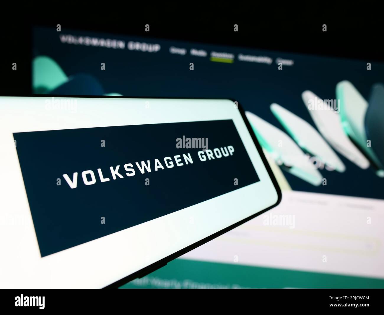 Smartphone with logo of German automotive company Volkswagen AG on screen in front of business website. Focus on center-left of phone display. Stock Photo