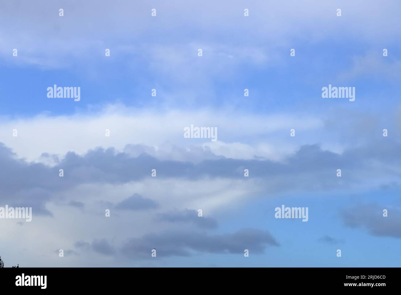 A cloudy winter sky backdrop. White and grey clouds on a mid blue sky. Stock Photo
