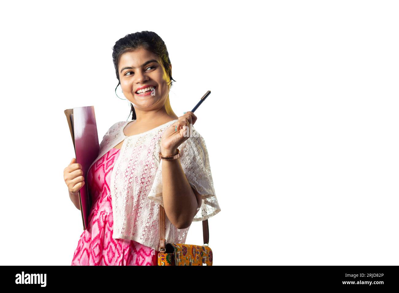 A pretty young Indian girl with books in hand pointing with smiling ...