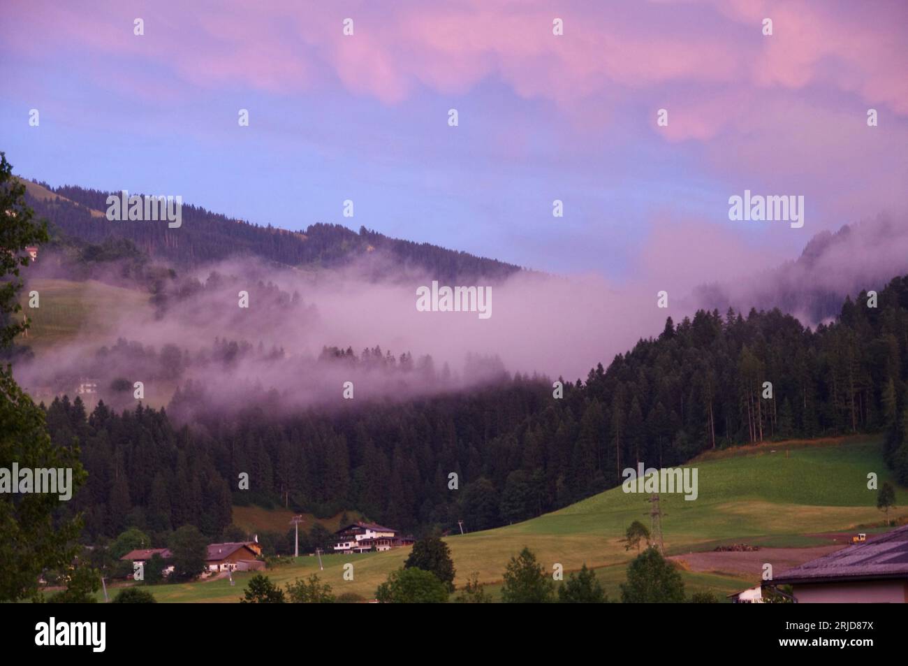 Söll, Austria,Mist rolling over the hillside under a pink sky. Stock Photo