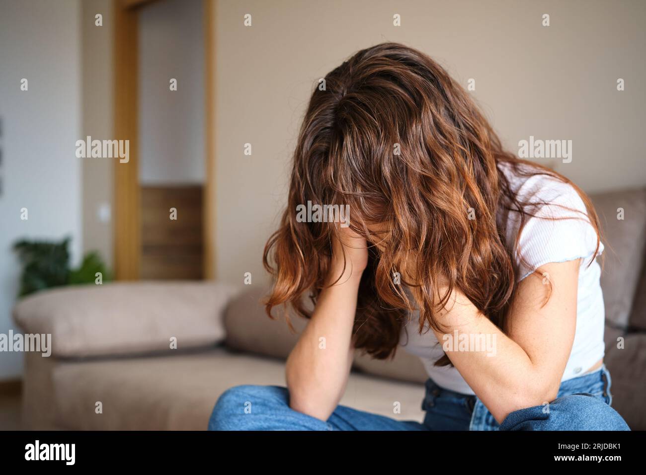 Sad woman covering the face with hands at home Stock Photo