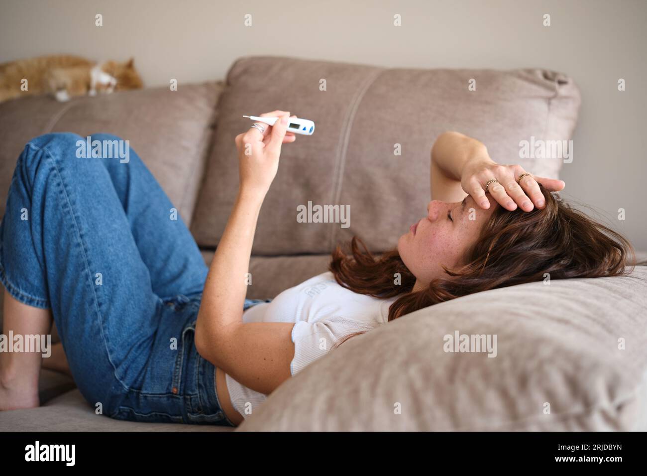 Woman feeling sick taking using a thermometer at home Stock Photo