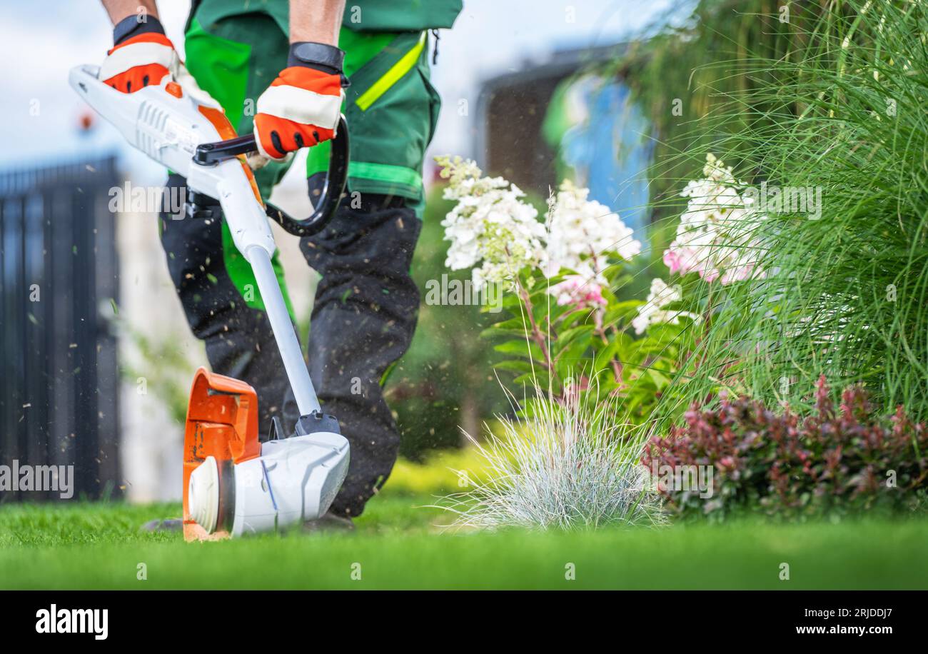 Professional Gardener with Lawn Edger Cutting Lawn Edges Close Up Photo