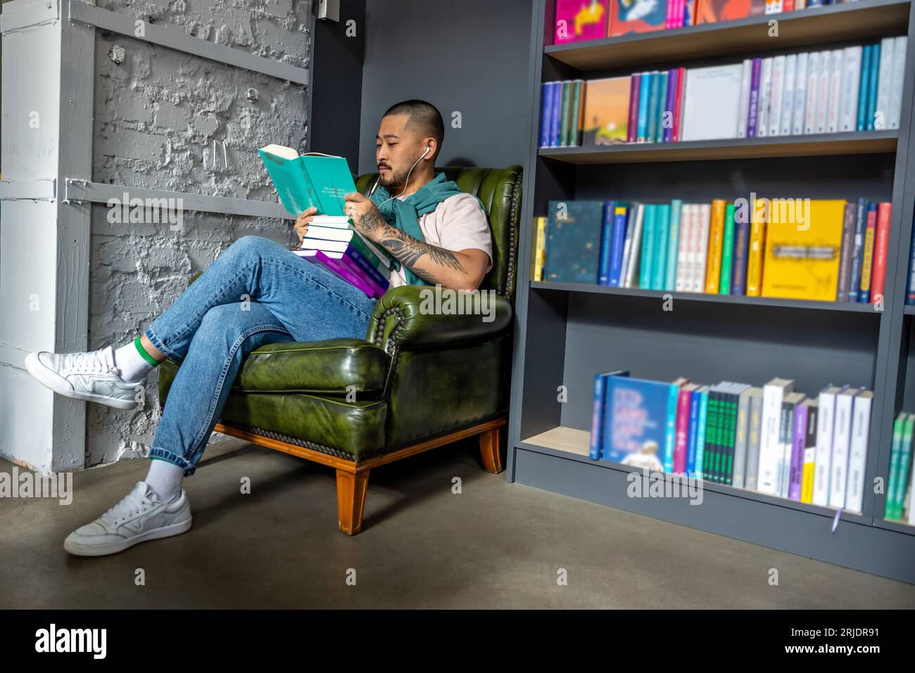 Young asian man sitting with a book in library Stock Photo - Alamy