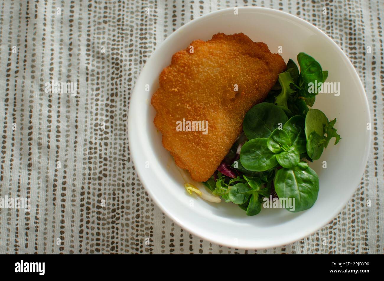Rissois de Camarao portuguese deep fried pastry pie with shrimps served with greens in white bowl on beige printed textile tablecloth. Food photograhy Stock Photo