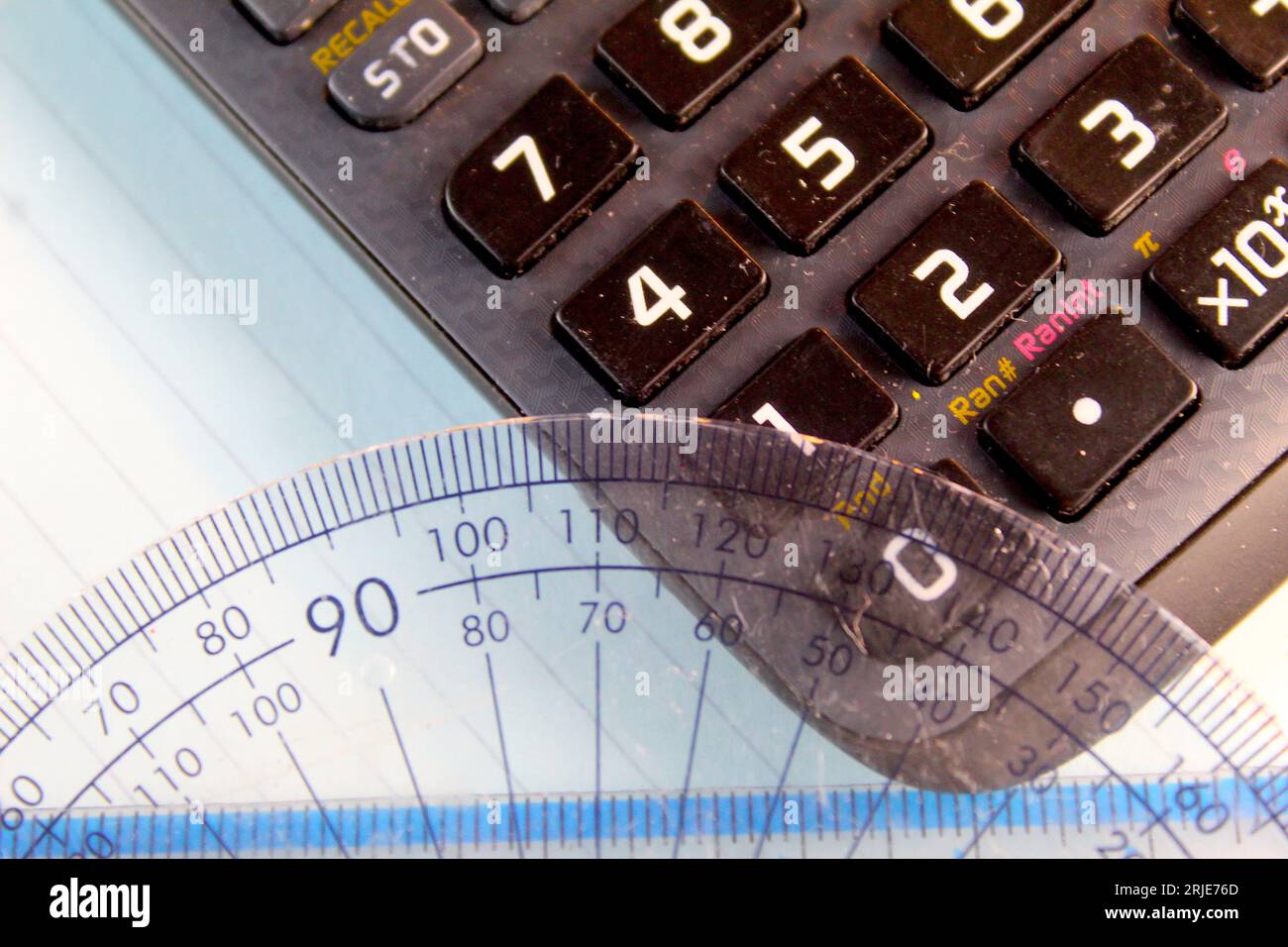 A photo of a mathematics protractor on top of a black calculator on a
