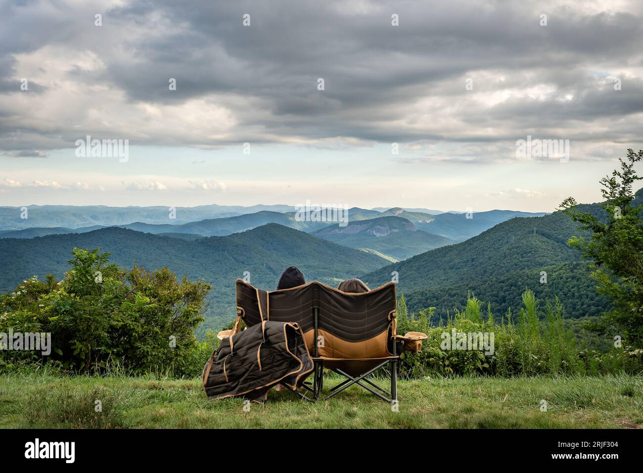 Couple sitting overlooking the Blue Ridge Mountains, Looking Glass Rock near Brevard, North Carolina Stock Photo