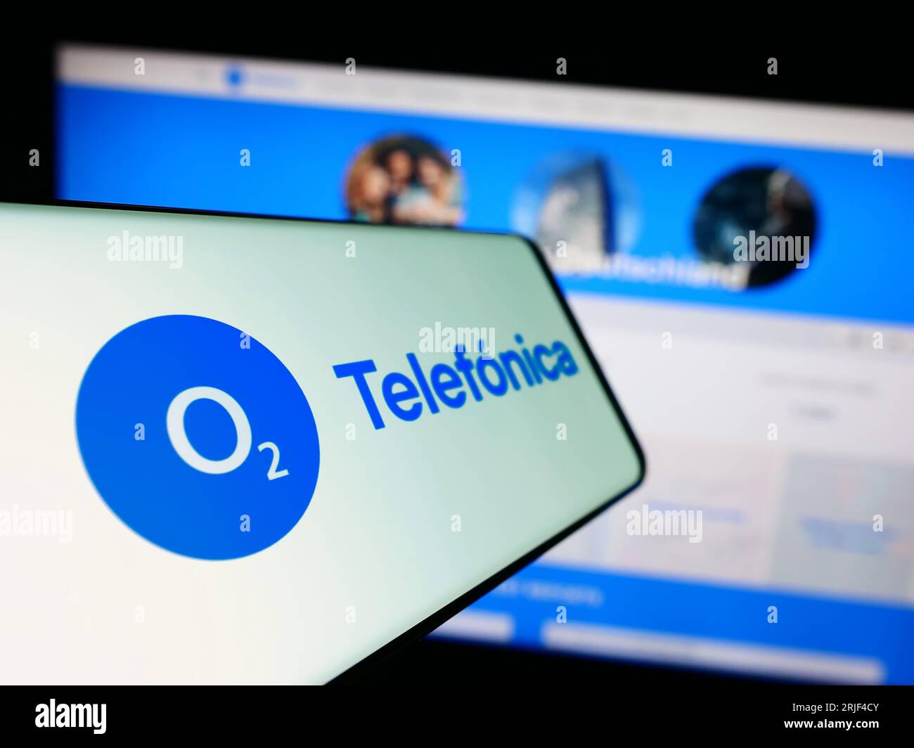 Mobile phone with logo of company Telefonica Deutschland Holding AG on screen in front of website. Focus on center-left of phone display. Stock Photo
