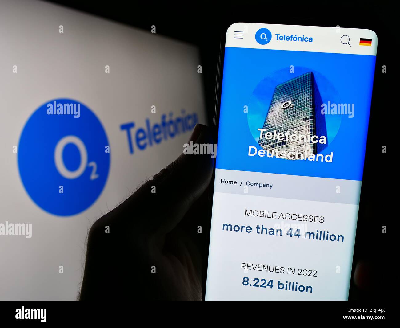 Person holding cellphone with webpage of company Telefonica Deutschland Holding AG on screen in front of logo. Focus on center of phone display. Stock Photo