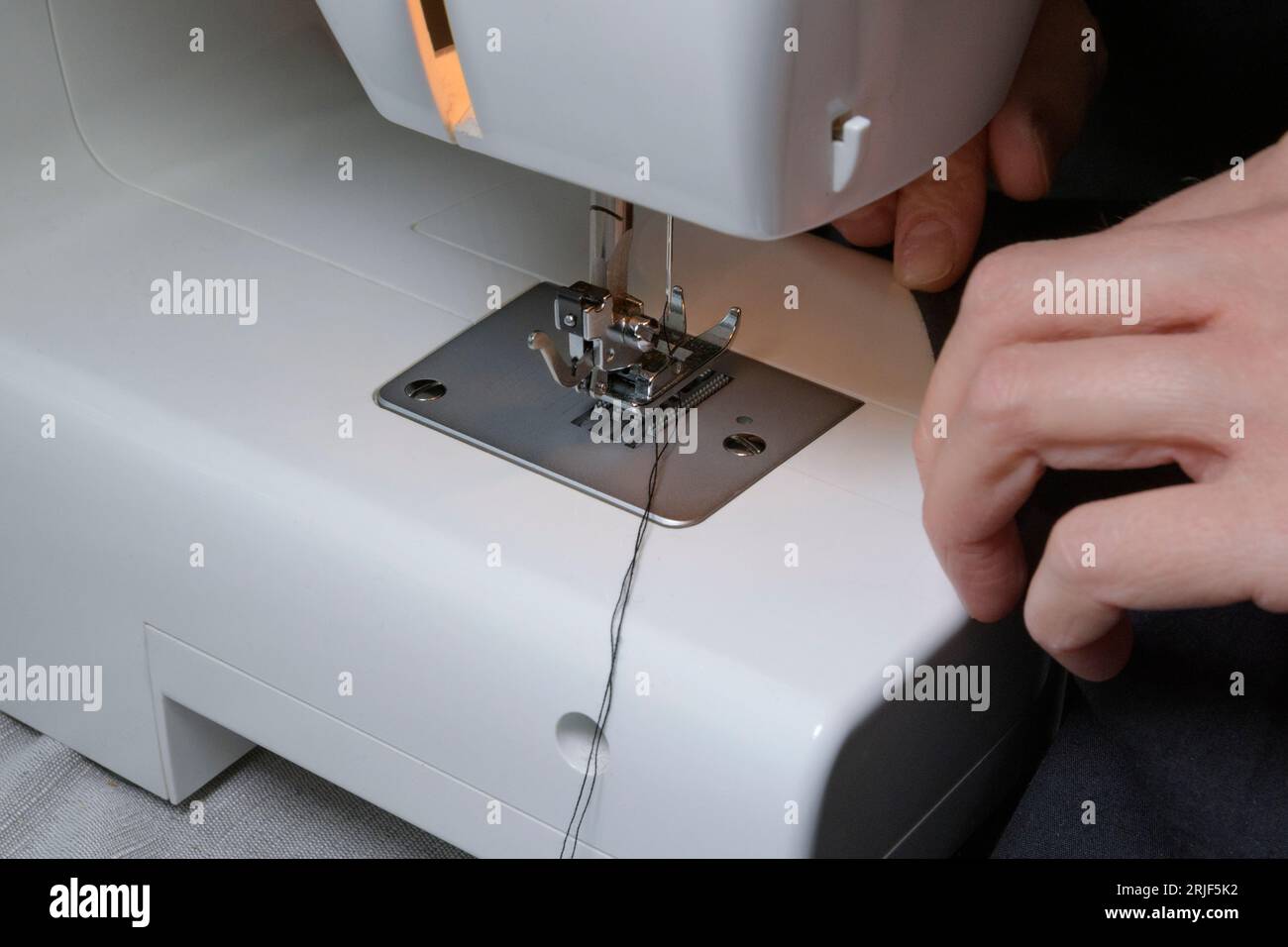 Process of sewing. The correct position of the threads under the needle. Home sewing machine at work. Close-up Stock Photo
