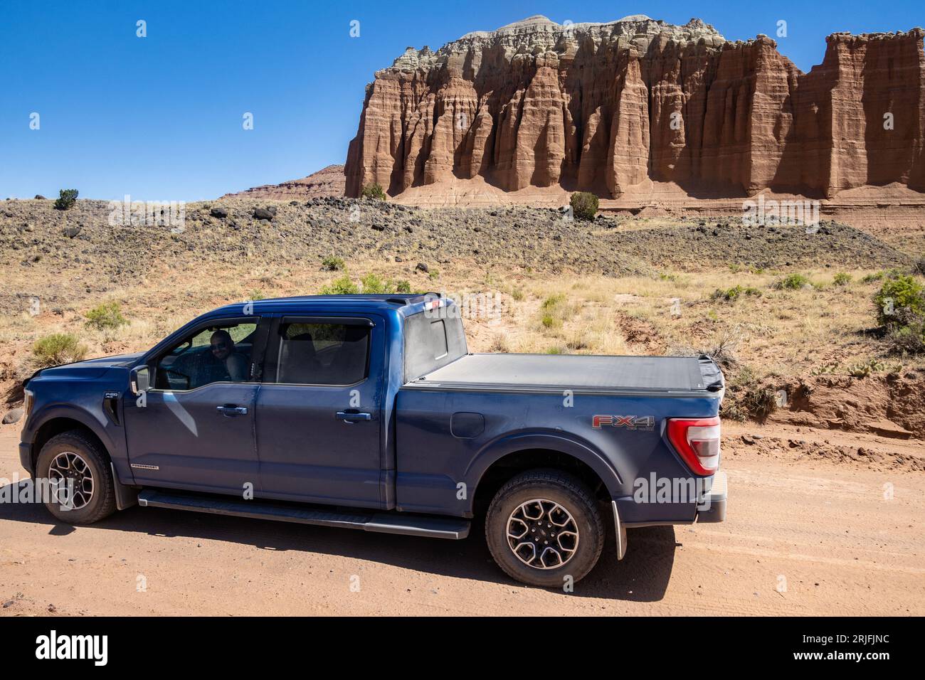 Blue Ford F-150 pickup truck off roading in the desert. Stunning rock formations in Capital Reef National Park, Utah, USA. They are called Cathedrals. Stock Photo