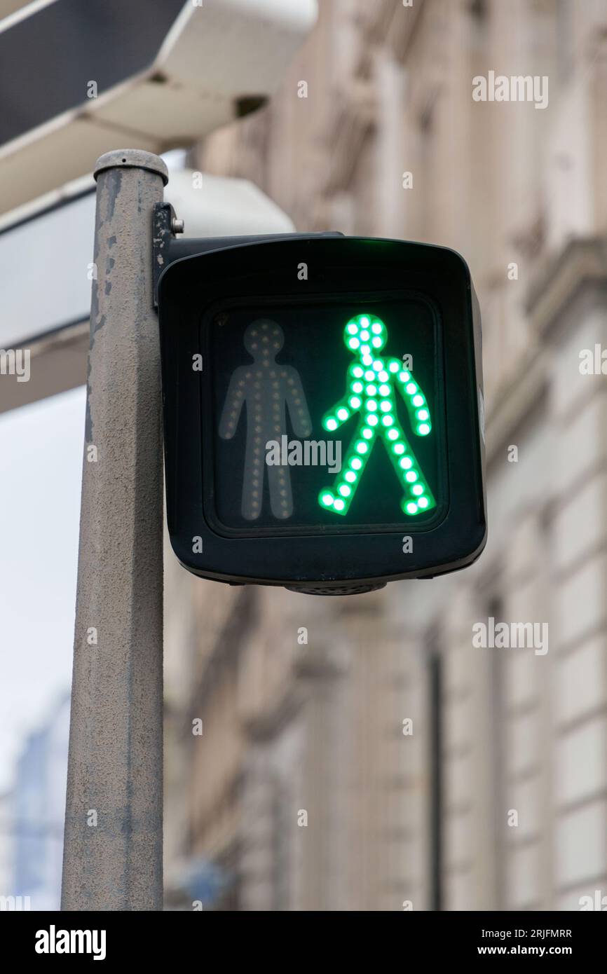 Green pedestrian light with a universal walking person icon in France. Stock Photo
