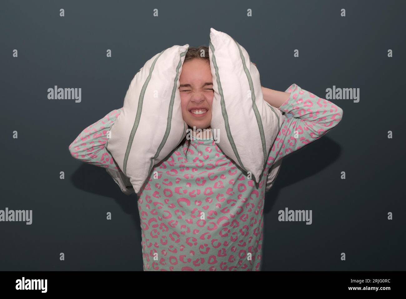 Teenage girl can't sleep. The girl covers her ears with pillows from a