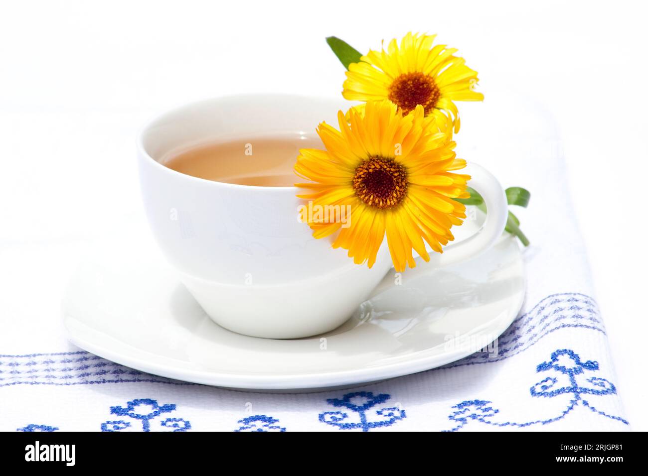 Cup of tea and calendula flowers on a kitchen towel Stock Photo