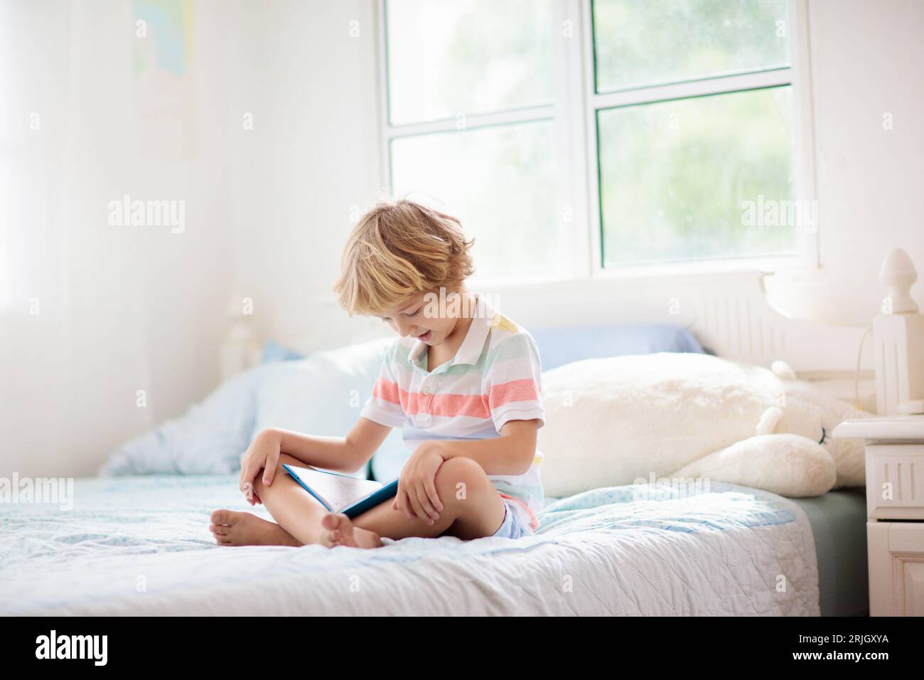Kids reading book in bed. Bedroom for child. Little boy reading books