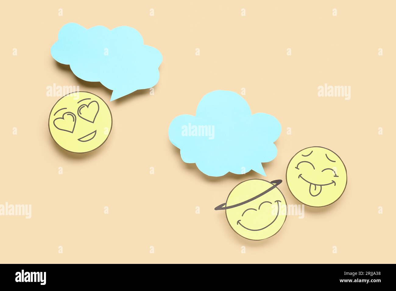 Paper faces with blank speech bubbles on beige background Stock Photo