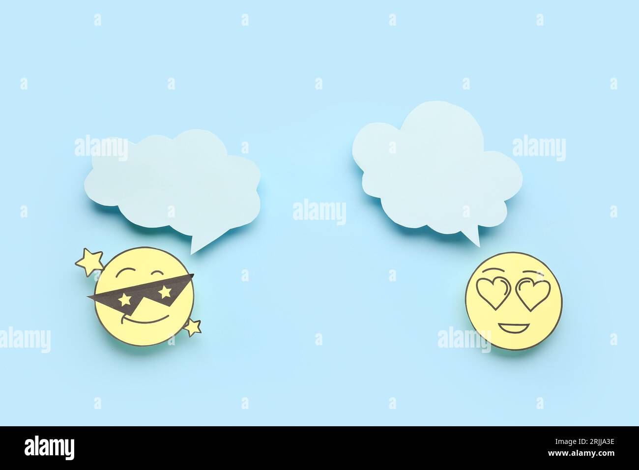 Paper faces with blank speech bubbles on blue background Stock Photo