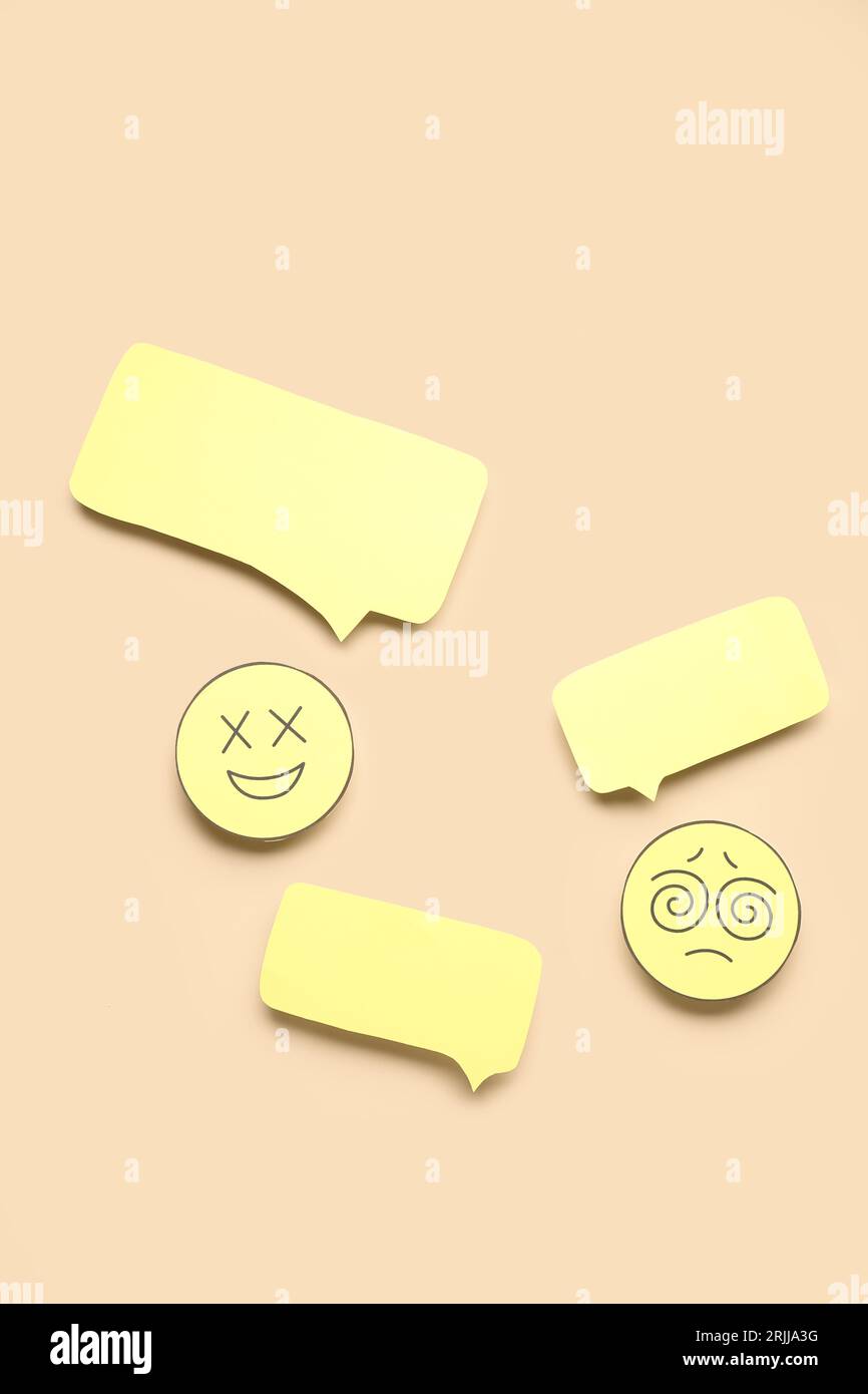 Paper faces with blank speech bubbles on beige background Stock Photo