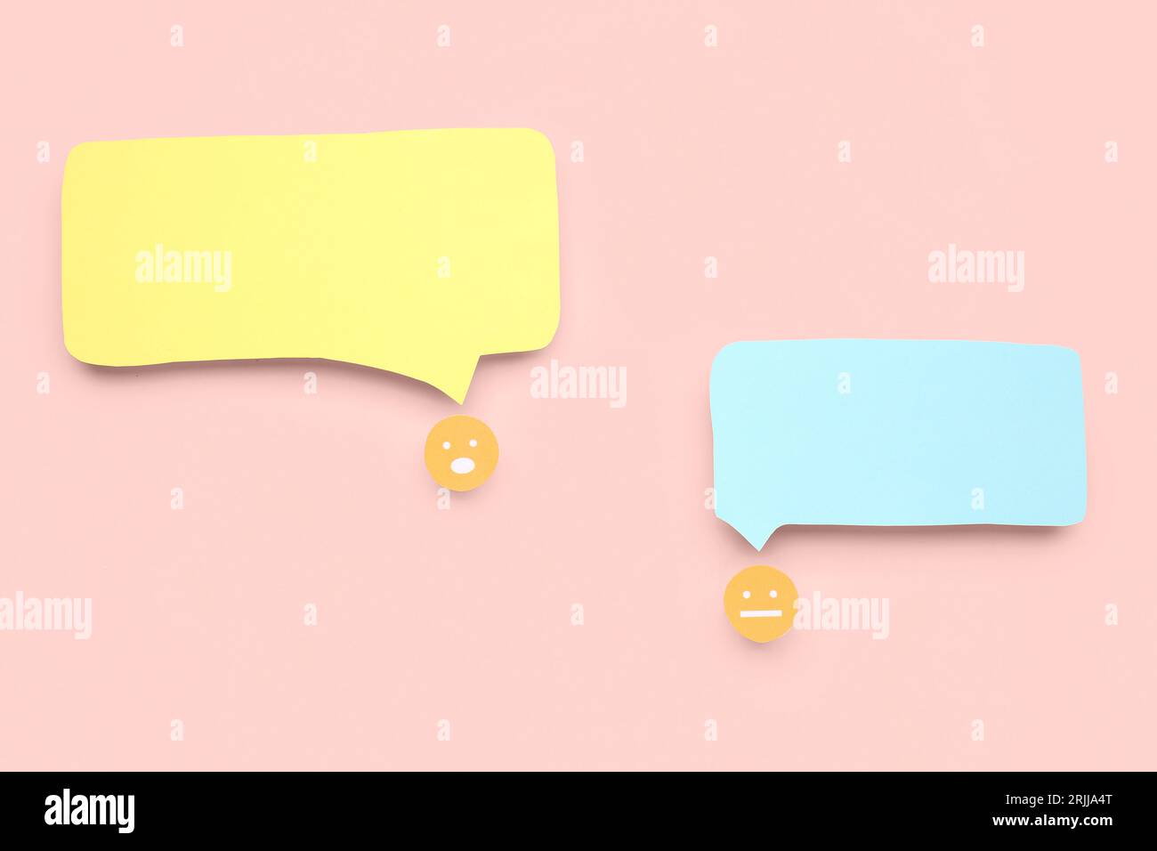 Paper faces with blank speech bubbles on pink background Stock Photo