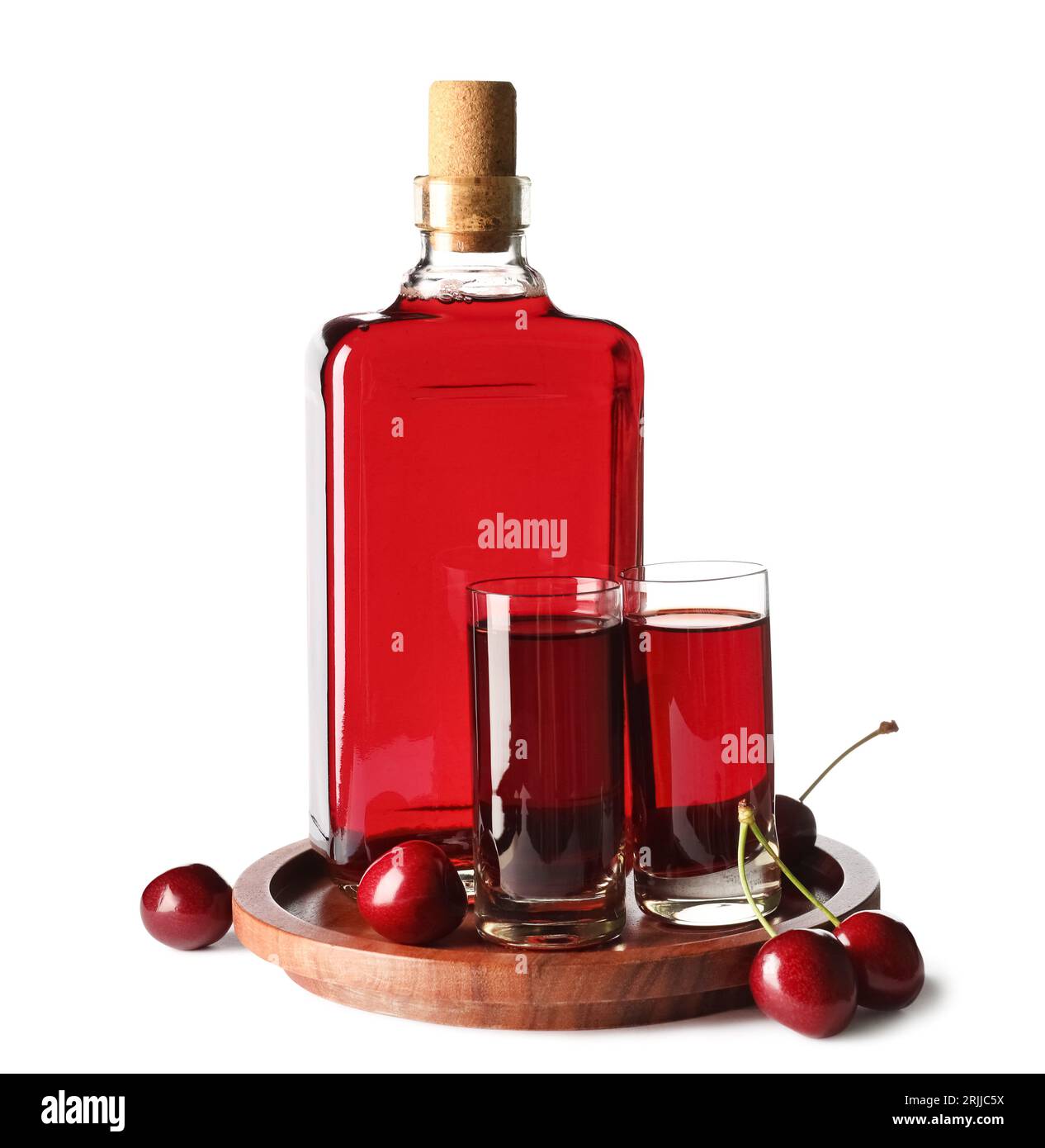 Glasses and bottle of sweet cherry liqueur with berries on white