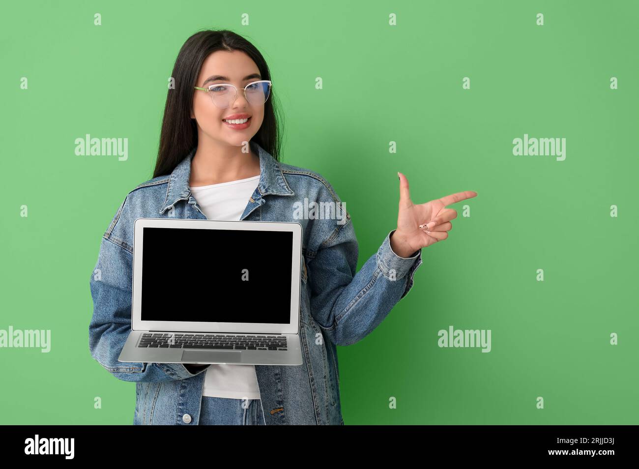Happy female programmer with laptop pointing at something on green ...