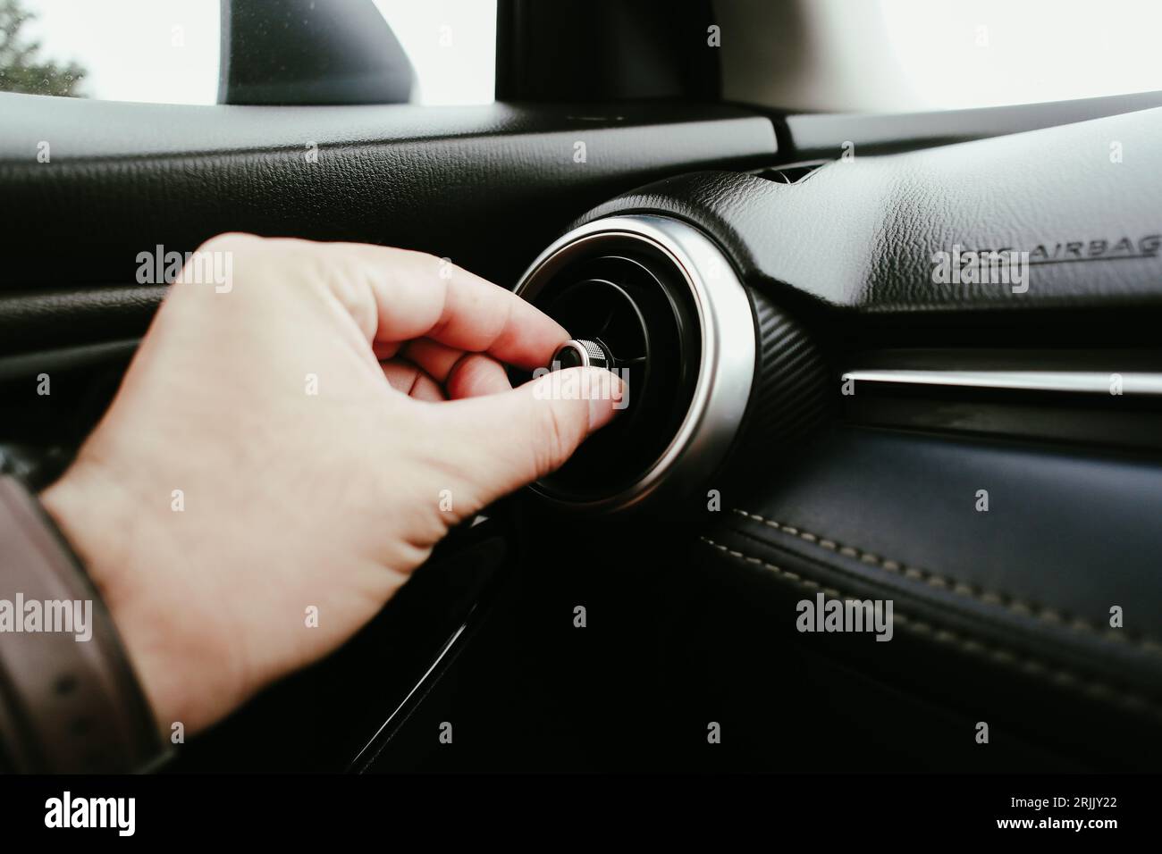 The driver hand adjusts the wind direction of the air vent in the car