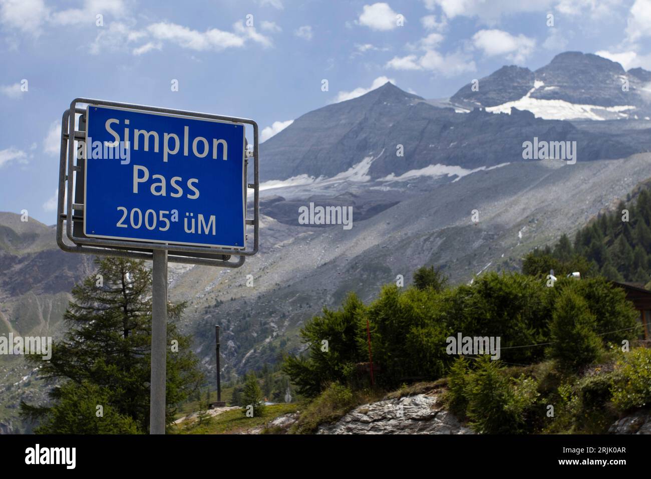 Road sign for the famous Simplon Pass in Switzerland, with height information and a background of mountains. Copy space to the right. Stock Photo
