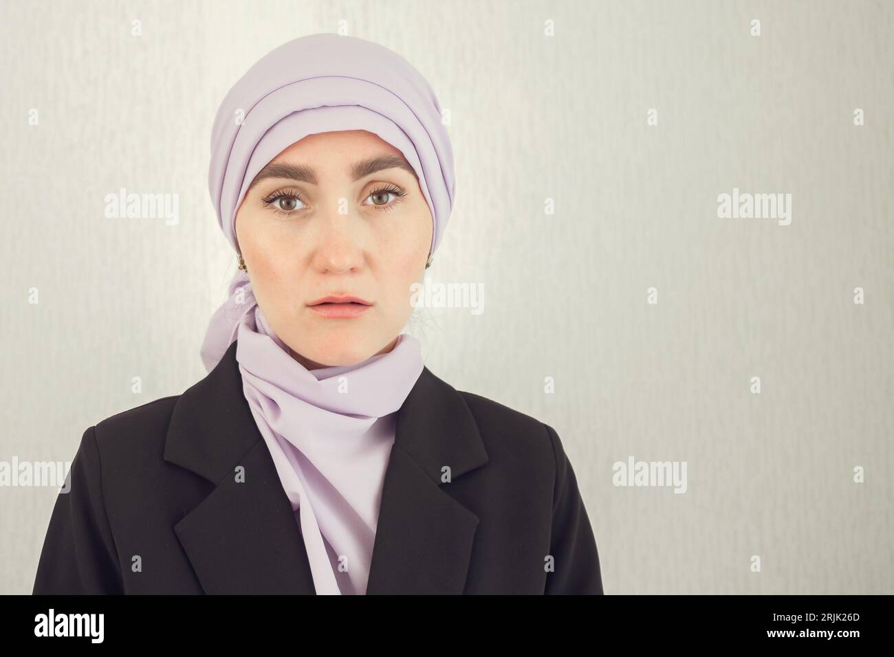 Muslim woman with excitement stands at white studio wall Stock Photo