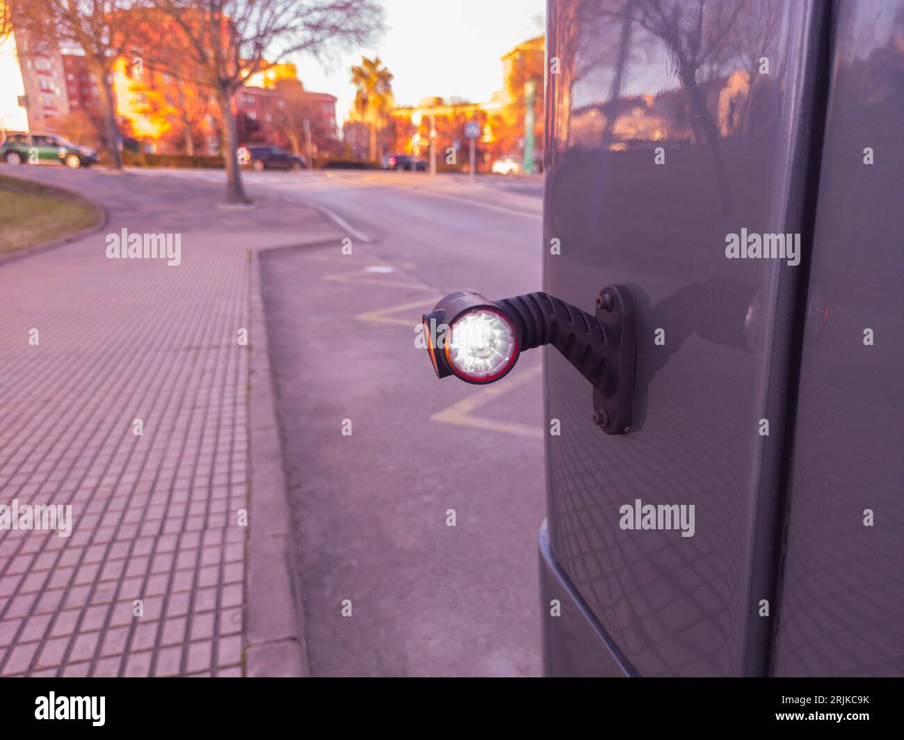 Rear side marker light attached on bus. Urban sunset background Stock